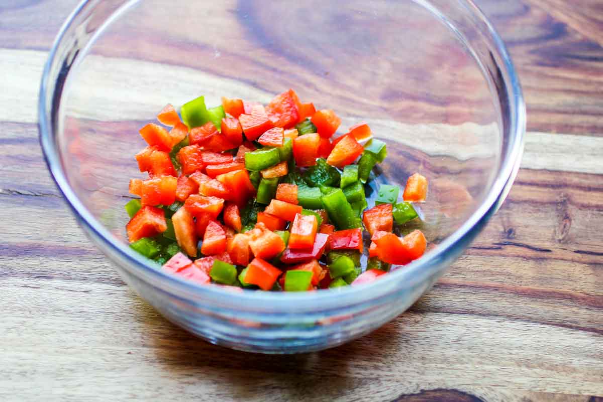 a glass bowl with chopped red and green peppers