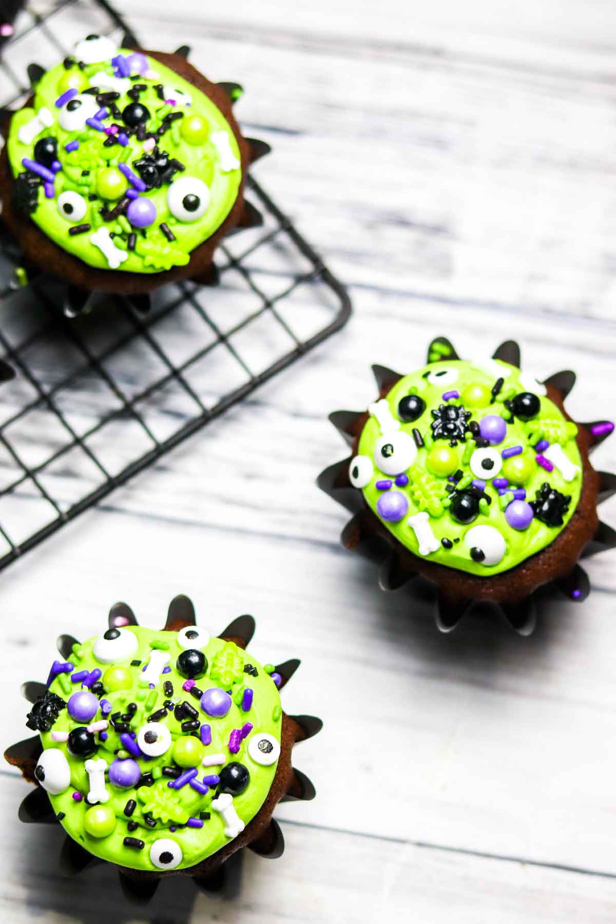 Three Chocolate Caramel Filled Cupcakes on a Cooling Rack Decorated for Halloween