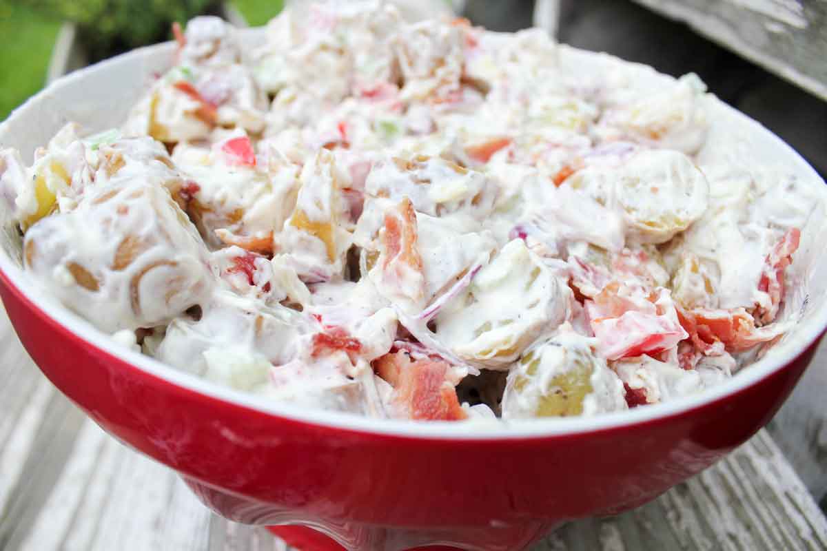 Creamy Potato Salad with Bacon in a Red Bowl Close Up