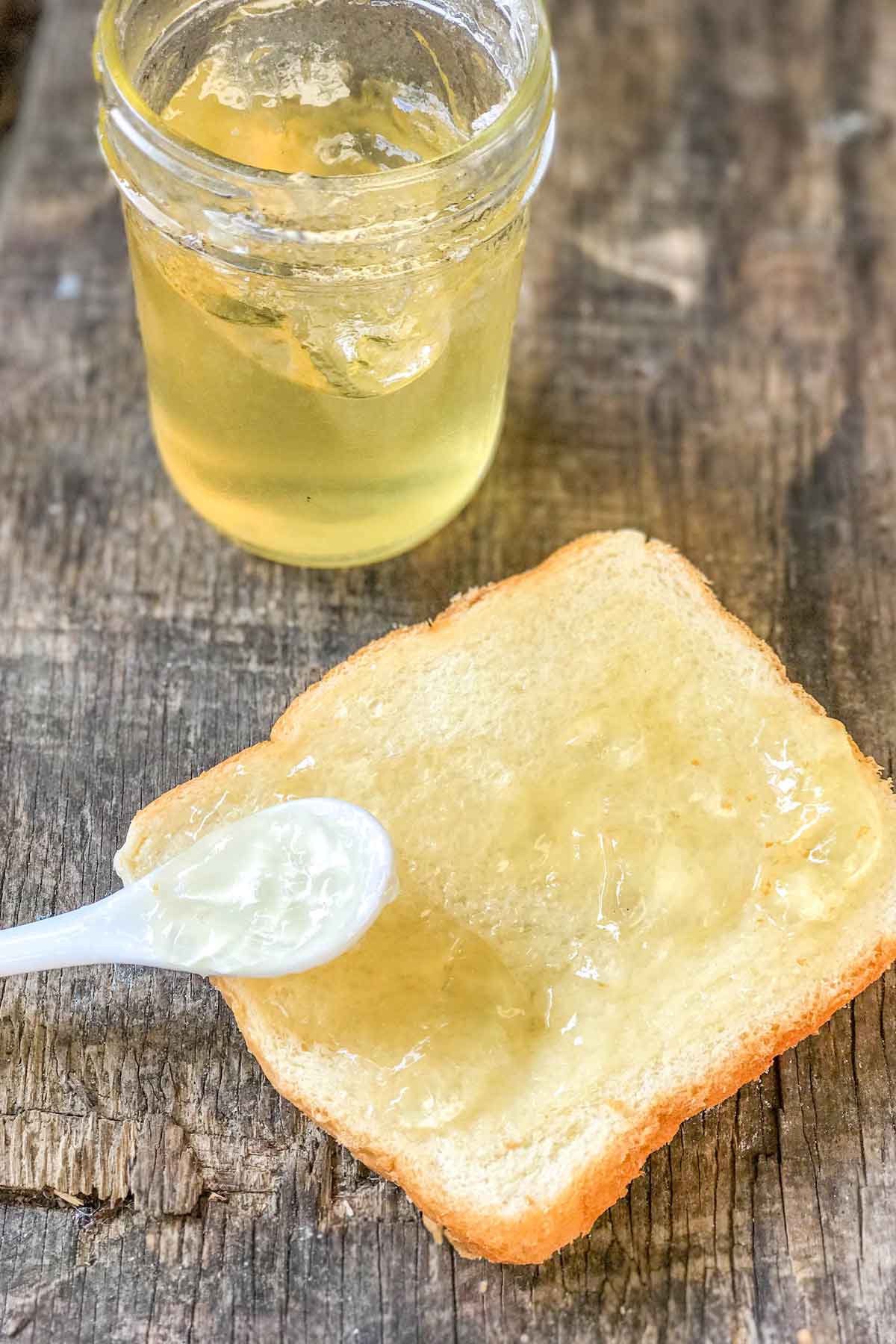Spooning Honeysuckle Jelly onto a slice of bread.