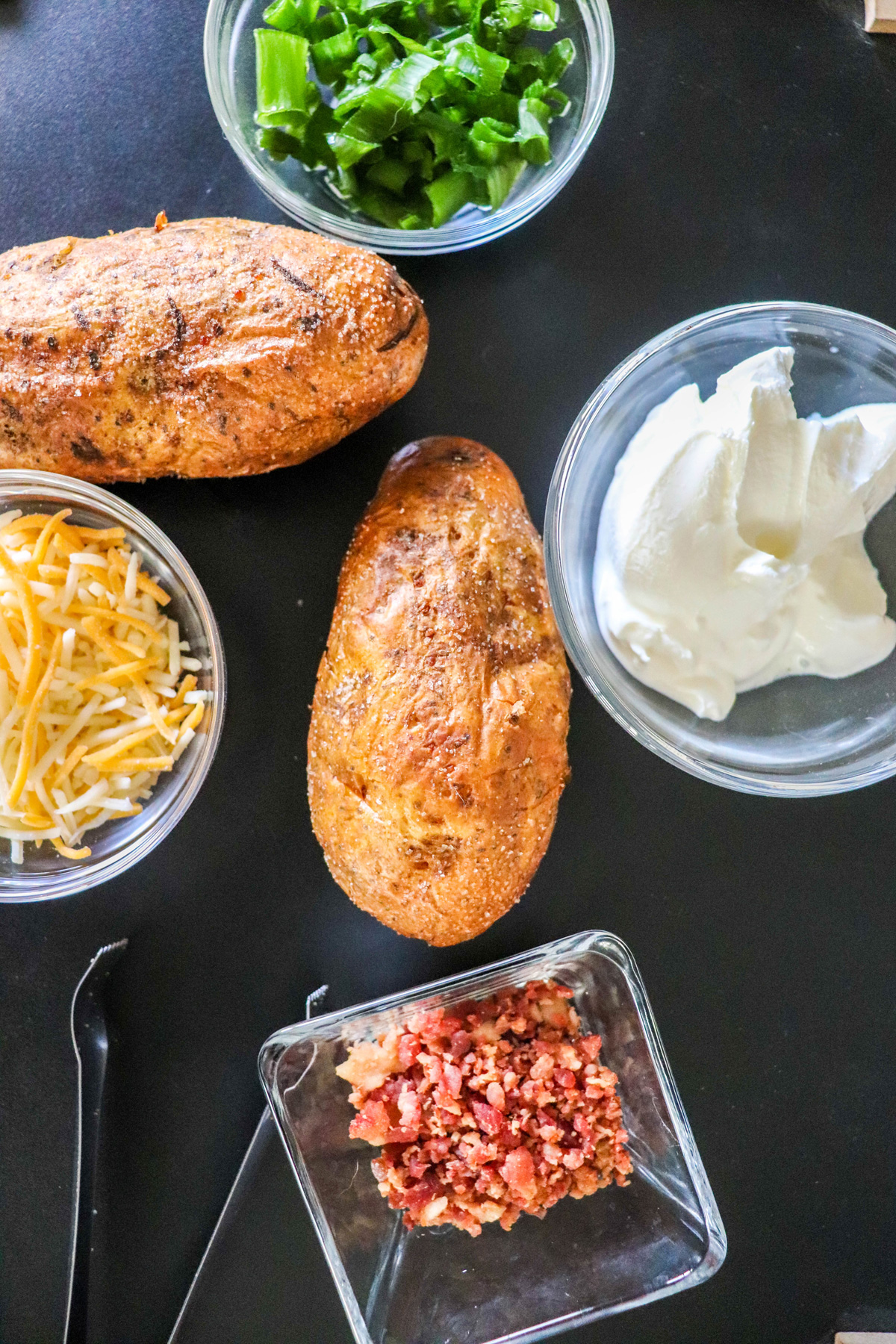 Air Fryer Baked Potatoes Overhead with ingredients surrounding the finished potatoes