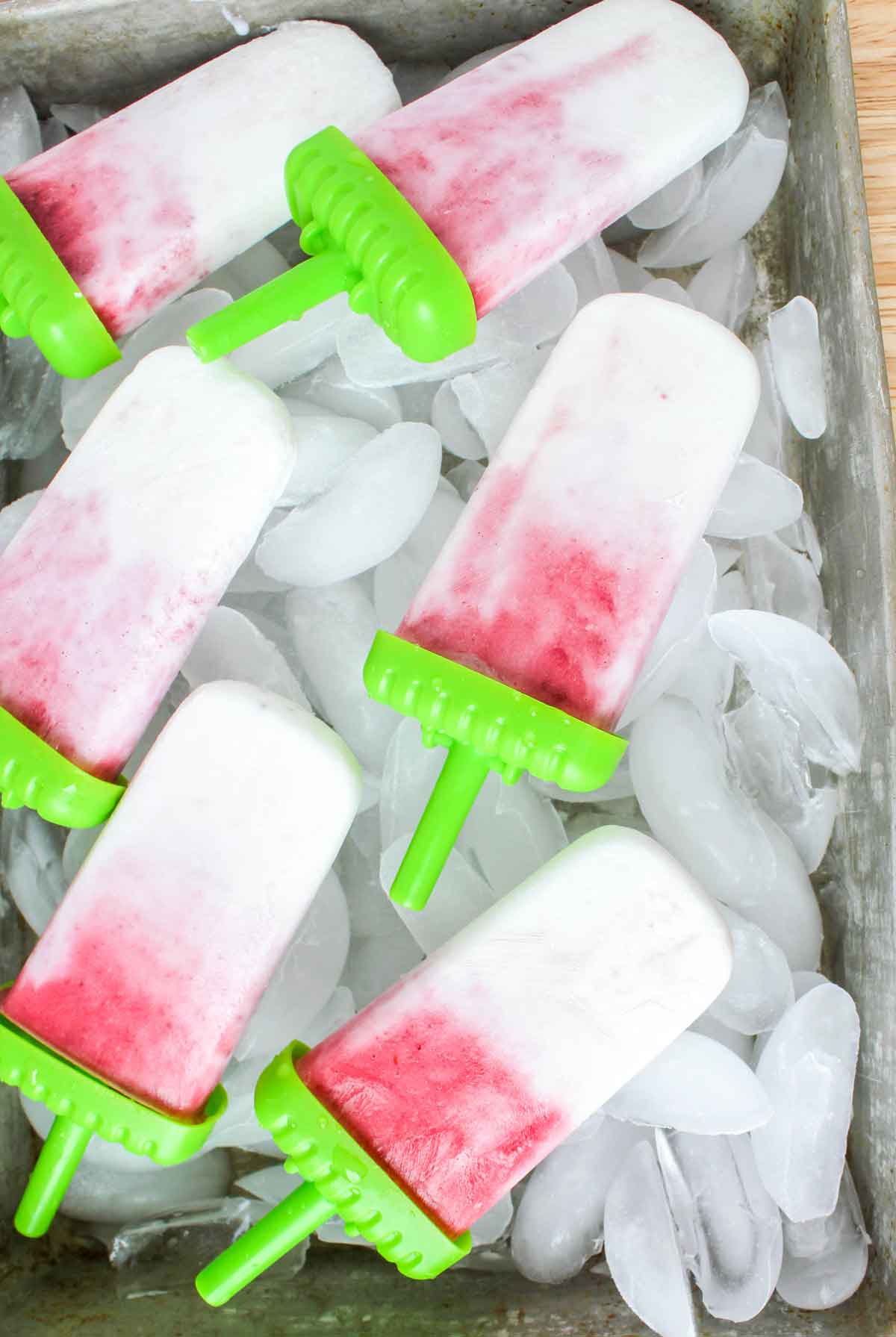Lots of Strawberry Coconut Ice Pops on a tray with ice